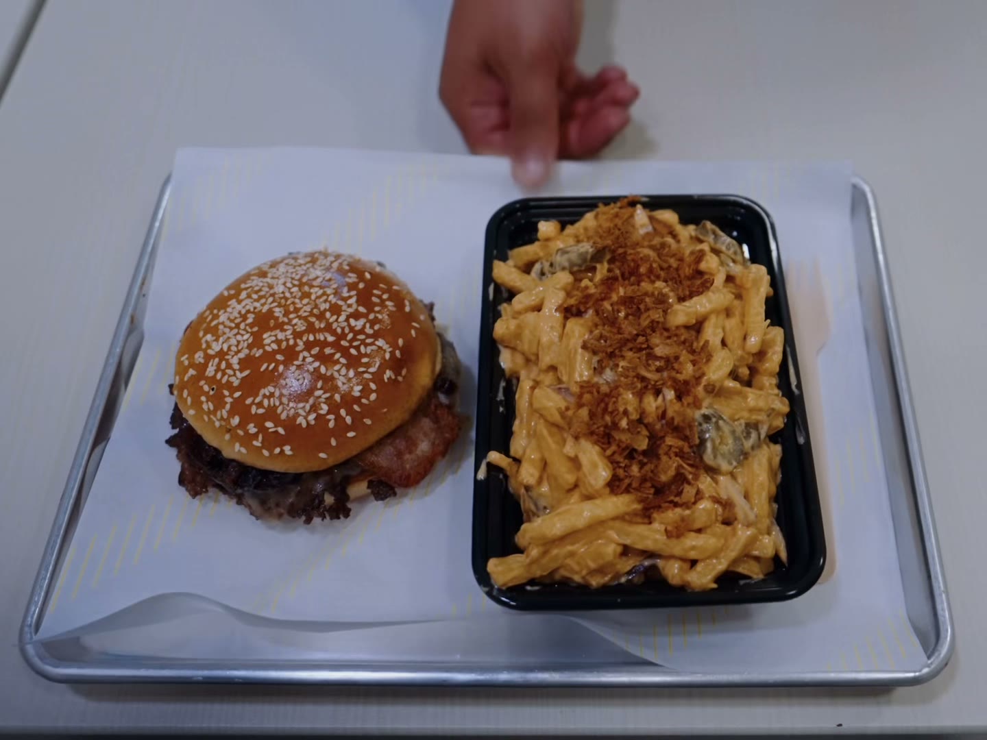 A burger and loaded fries on a steel tray