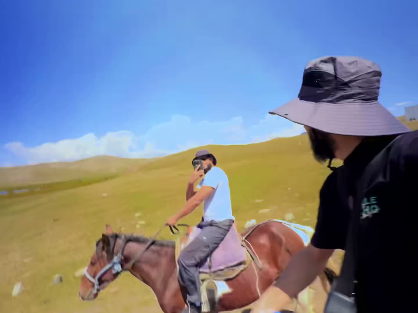 A rider on horseback in green hills under a blue sky