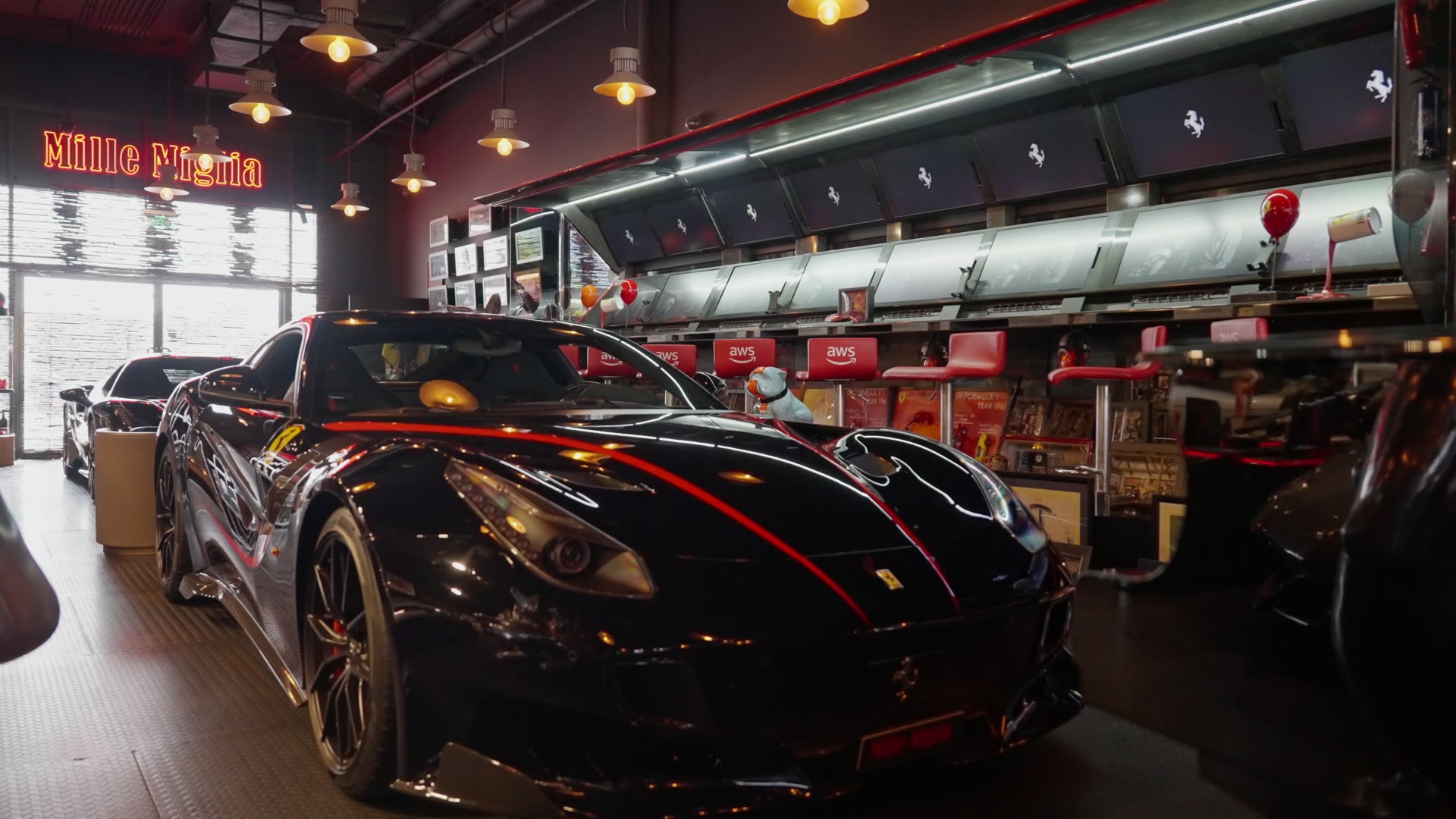 A black Ferrari with a red stripe parked inside a café under a Mille Miglia sign