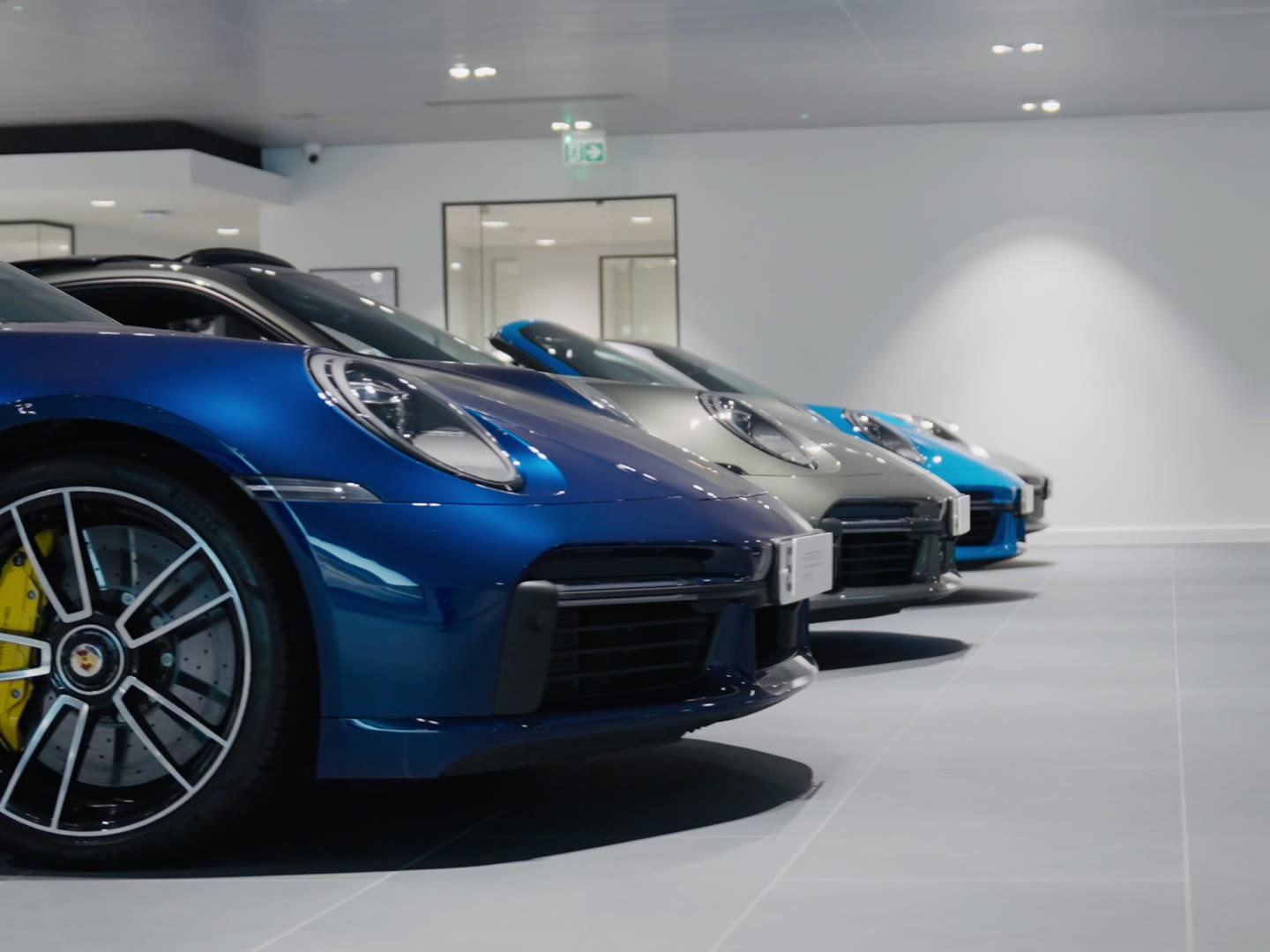 A row of blue Porsches in a white showroom